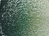 Aerial view of a surfer swimming in the ocean waves in Peniche,Portugal