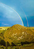 Aerial view of vibrant double rainbow over lush hilltop,North Berwick Law,Scotland