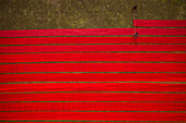 Aerial view of two people working in a field stretching red cloth in Narsingdi,Dhaka,Bangladesh