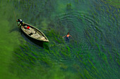 Sirajganj,Bangladesh - 23 December 2018: Aerial view of two person on a wooden canoe crossing a river full of algae in Sirajganj,Bangladesh