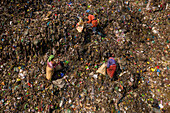 Dhaka,Bangladesh - 20 October 2020: Aerial view of three women collecting rubbish in a big wasting dump at Mutual Waste treatment plant,Dhaka,Bangladesh