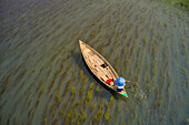 Aerial view of a fisherman wearing a traditional hat and sailing the Bengali river near Ullahpara town,Rajshahi,Bangladesh