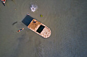 Aerial view of a few kids playing and swimming in Buriganga river,jumping from a wreck old boat,Dhaka,Bangladesh