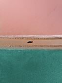 Aerial view of the pink Lake McDonnell with a car driving on the road that divides the pink salt from the blue water,Eyre Peninsula,Australia. Top down perspective