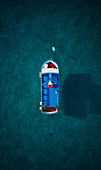Aerial view of a little tourist boat at morning surrounded by a transparent blue sea moored in the Ionian Sea,Calabria,Italy