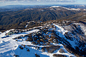 Aerial view of snowy Mount Buller ski resort surrounded by majestic woods and alpine terrain,Victoria,Australia