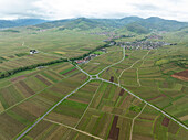 Luftaufnahme einer ruhigen ländlichen Landschaft mit üppigen Feldern und einem malerischen Dorf, umgeben von Bergen, Kaysersberg, Frankreich