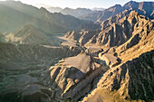 Luftaufnahme eines Canyons zwischen felsigen und trockenen Bergen in der Wüste im Staat Ajman, Vereinigte Arabische Emirate