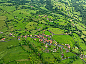 Luftaufnahme eines üppig grünen Dorfes mit Feldern, Bäumen und Wiesen in Infiesto, Asturien, Spanien