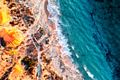 Aerial view of a rugged shoreline and white sandy beach with clear blue water and calm long exposure waves rolling onto the shore,Port Noarlunga,South Australia,Australia