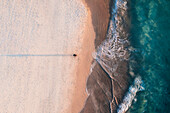 Aerial view of a photographer on the beach from above with blue ocean water and long exposure effect on the waves,Port Noarlunga,South Australia,Australia