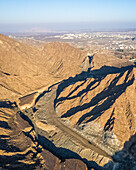 Luftaufnahme eines Canyons zwischen felsigen und trockenen Bergen in der Wüste im Staat Ajman, Vereinigte Arabische Emirate