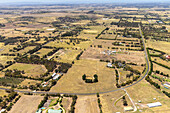 Luftaufnahme von ausgedehntem Ackerland und einer friedlichen Landschaft mit Häusern und Bäumen unter einem klaren Himmel, Diggers Rest, Australien