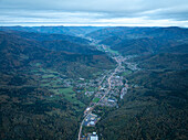 Luftaufnahme einer malerischen Stadt, umgeben von üppigen Bergen und einem ruhigen Tal, Thann, Haut-Rhin, Frankreich