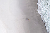Luftaufnahme eines ruhigen Strandes mit einer sonnenbadenden Frau, Melkbosstrand, Südafrika