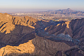 Luftaufnahme eines Canyons zwischen felsigen und trockenen Bergen in der Wüste im Staat Ajman, Vereinigte Arabische Emirate