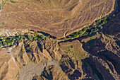 Luftaufnahme eines Canyons zwischen felsigen und trockenen Bergen in der Wüste im Staat Ajman, Vereinigte Arabische Emirate