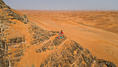 Aerial view of two girls on a rocky mountain in the Camel Rock Desert Safari in UAE
