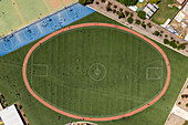 Aerial view of sports field and running track surrounded by buildings and trees,Melton West,Australia