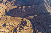 Luftaufnahme eines Canyons zwischen den felsigen und trockenen Bergen in der Wüste im Staat Ajman, Vereinigte Arabische Emirate