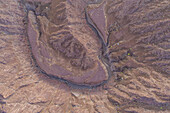 Luftaufnahme eines Canyons zwischen den felsigen und trockenen Bergen in der Wüste in Ajman State, Vereinigte Arabische Emirate