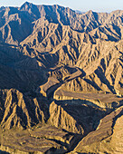 Luftaufnahme eines Canyons zwischen den felsigen und trockenen Bergen in der Wüste im Bundesstaat Ajman, Vereinigte Arabische Emirate