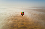 Aerial view of a group of hot-air-balloon flying in the clouds of the Murqquab desert in Dubai,U.A.E