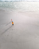Luftaufnahme von Menschen, die am Sandstrand am Meer spazieren gehen, Melkbosstrand, Westkap, Südafrika