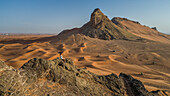 Aerial view of a girl on the top of a rocky mountain in the Camel Rock Desert Safari in UAE