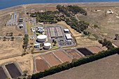 Aerial view of a water treatment plant with storage tanks,ponds,and solar panels surrounded by greenery and fields,Wurdiboluc,Australia