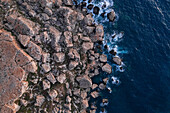 Luftaufnahme von Wellen, die an die Klippen entlang der Küste von Quarraba Bay, Mgarr, Malta schlagen