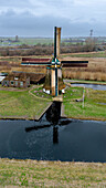 Aerial view of a picturesque windmill near a tranquil canal surrounded by lush green grass,Weesp,The Netherlands