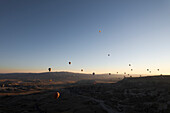 Aerial view of hot air balloons over a serene valley at sunrise with majestic rock formations,Goreme,Turkey