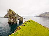 Aerial view of man standing in front of Drangarnir rock formation,Faroe island