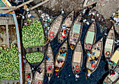 Luftaufnahme des geschäftigen Handels mit großen Schiffen, die Wassermelonen entladen, und kleinen Fährbooten auf dem verschmutzten Buriganga-Fluss, Dhaka, Bangladesch