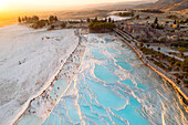Aerial view of white cotton castle at sunset with travertine terraces and thermal pools,Pamukkale,Turkey