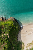 Aerial view of Lantic Bay,Fowey with people on the beach enjoying the sunshine,turquoise blue sea and lush green foliage,Cornwall,United Kingdom