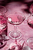 Crystal glasses and ice cubes on a pink background