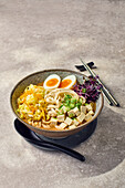 Ramen with rice noodles, egg, tofu, pointed cabbage and radish sprouts