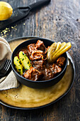 Pepper pot pie with fried potato wedges and pickled cucumber