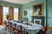 Elegantes Esszimmer mit pastellblauen Wänden, weihnachtlich gedeckter Tafel und Gartenblick