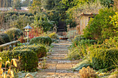 Frostbedeckter Gartenweg mit Statuen und Vogelhäuschen im Winter