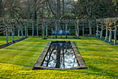 Geometrisch geschnittener Garten mit rechteckigem Teich im Winter
