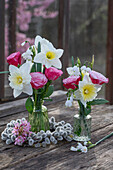 Narzisse, Schneeglöckchen und Rosen in Vase mit Kranz aus Weidenkätzchen und Bergenie 