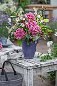 Blumenstrauß mit Hortensie, Zierapfel, Berufkraut (Erigeron 'Sommerneuschnee'), Mutterkraut und Giersch im Krug auf dem Gartentisch