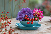 Hortensie, Dahlie, und Hagebutten (Rosa multiflora) in Schalen arrangiert