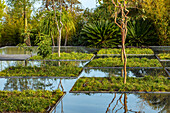 Wassergarten mit Bäumen und Wasserspiegelungen und geometrischen Beeten