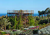 Holzturm umgeben von üppiger mediterraner Vegetation mit Meerblick