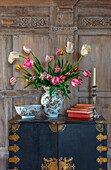 Tulpenarrangement in antiker Vase auf schwarzem Schrank im Flur