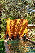 Schmaler Pool mit terrakottafarbener Wand und Olivenbäumen im Garten